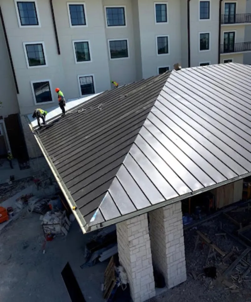 Crew installing standing seam metal roof panels on a commercial project in Grain Valley